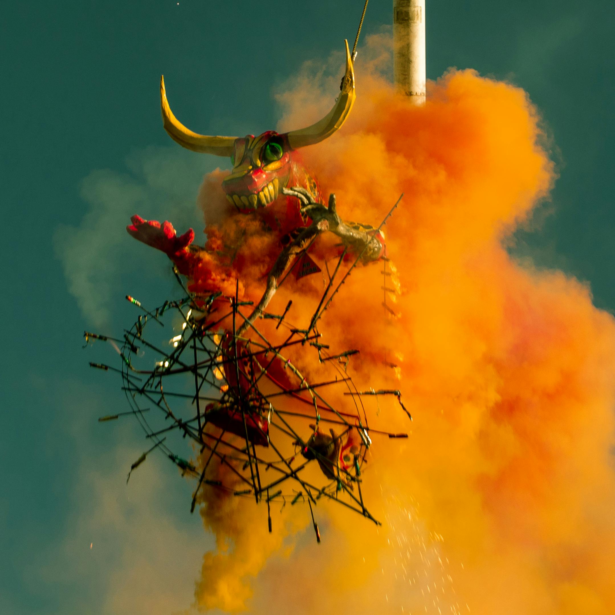 mars u biku kvadrat pluton u vodenjaku. velika rogata figura okružena gustim narančastim dimom i vatrom tijekom festivala ili performansa.
